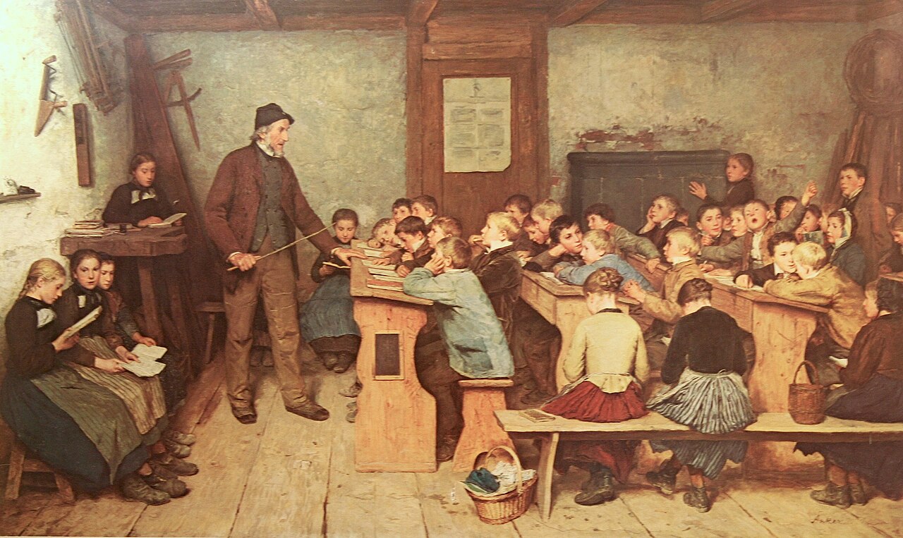 Painting of a crowded wooden schoolroom. An older teacher in a dark hat and brown coat stands with a pointer among rows of children at benches; some read, some raise their hands, and several girls sit reading at the left.