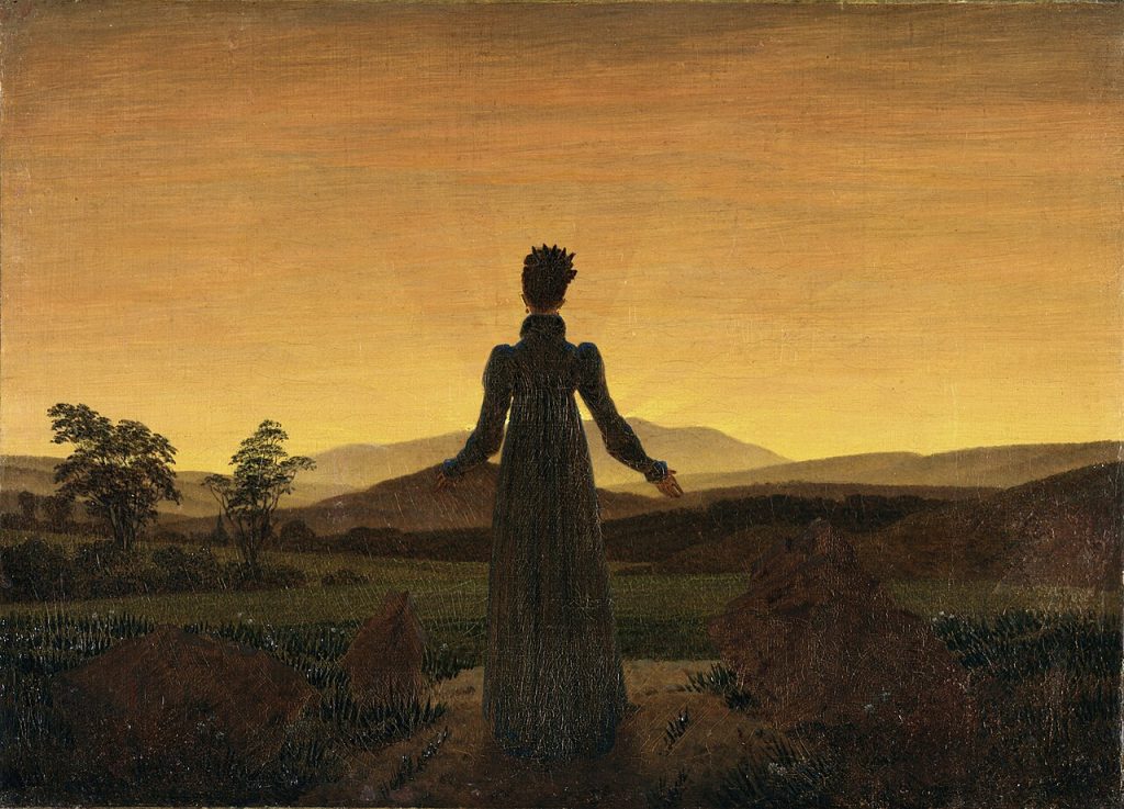 A painting of a woman in a long dark dress, seen from behind, standing on a path in a grassy field with her arms held slightly open toward a golden sky, the sun low behind distant hills.