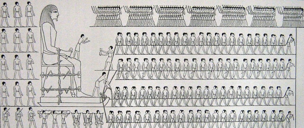 Black-and-white line drawing of an ancient Egyptian scene: a huge seated statue tied with ropes onto a sledge, a small figure standing on its knee, a man at the front of the sledge pouring liquid from a jar, and four long rows of men hauling on ropes, with a row of figures across the top and more men standing and carrying loads at the left.