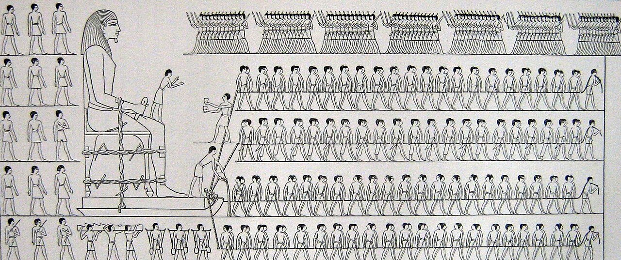 Black-and-white line drawing of an ancient Egyptian scene: a huge seated statue tied with ropes onto a sledge, a small figure standing on its knee, a man at the front of the sledge pouring liquid from a jar, and four long rows of men hauling on ropes, with a row of figures across the top and more men standing and carrying loads at the left.