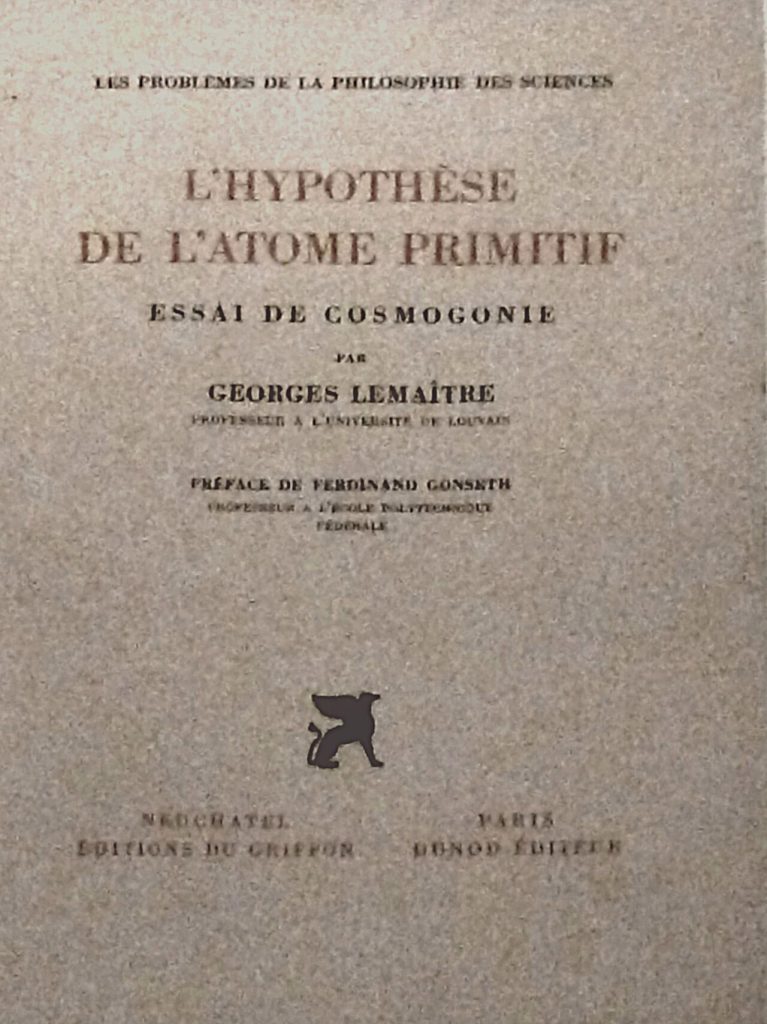 Cover of a speckled gray-beige French book. The title L’Hypothèse de l’Atome primitif is printed in large reddish-brown capital letters, with the subtitle Essai de cosmogonie and the name Georges Lemaître in black below it. A small black griffin emblem sits near the bottom, above the publishers’ names in Neuchâtel and Paris.