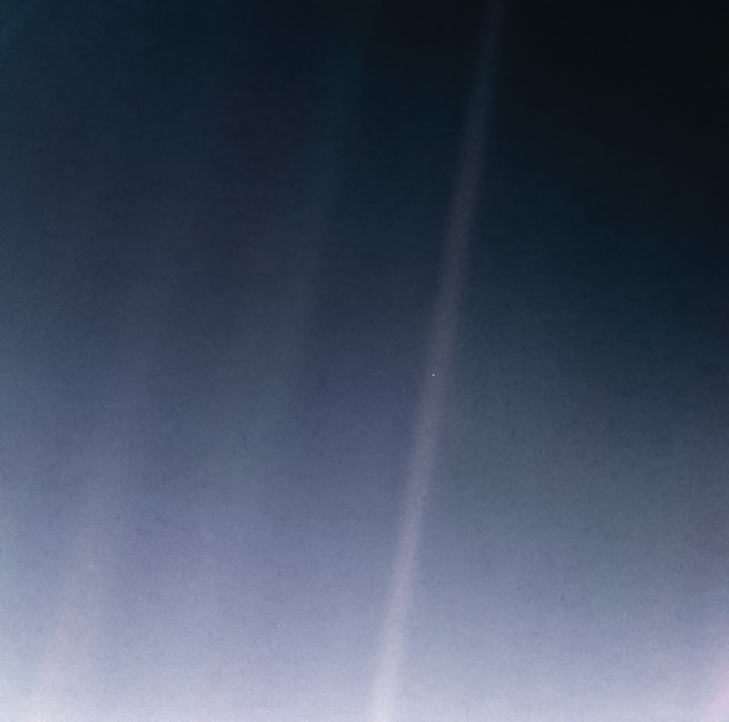 A dark blue-gray field of space crossed by faint pale streaks of scattered sunlight. In the middle of one streak, just right of center, is a single tiny bright dot.