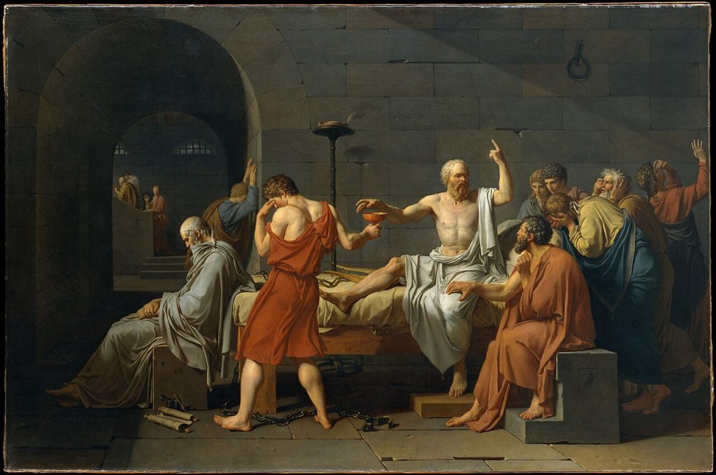 Painting of a prison cell. A white-bearded man, bare-chested and draped in white, sits upright on a bed, one hand raised as he talks and the other reaching for a cup held out by a young man who turns his face away. Grieving friends surround him.