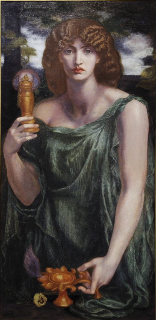 Oil painting of a woman with thick, wavy auburn hair and a serious gaze, in a flowing green robe. She holds up a tall golden vessel in one hand and rests the other on a small golden oil lamp shaped like a flower, with a pale yellow pansy beside it, against dark trees and a cloudy sky.