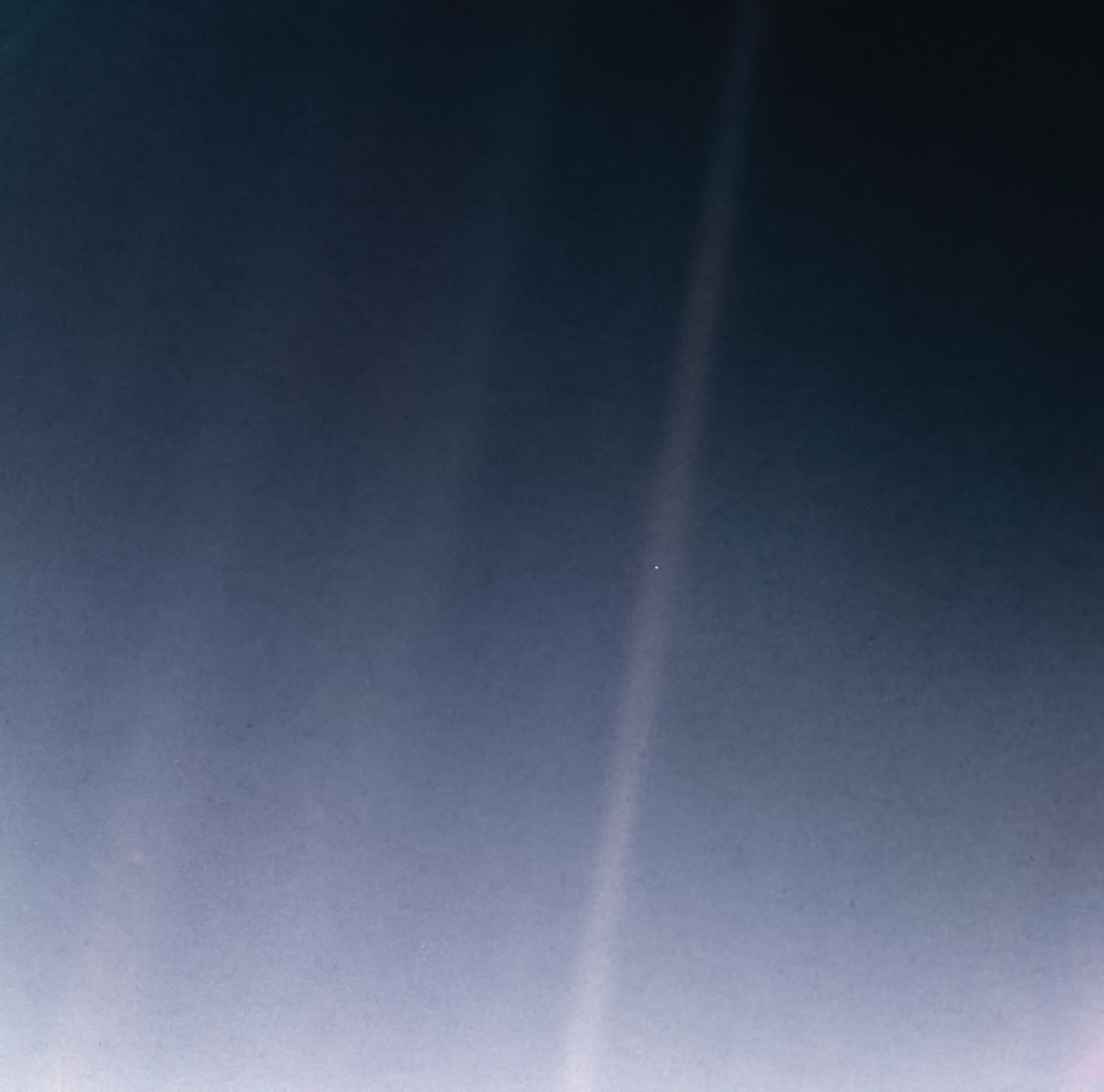 A tiny pale blue dot, Earth, sits inside a faint beam of scattered sunlight against black space.