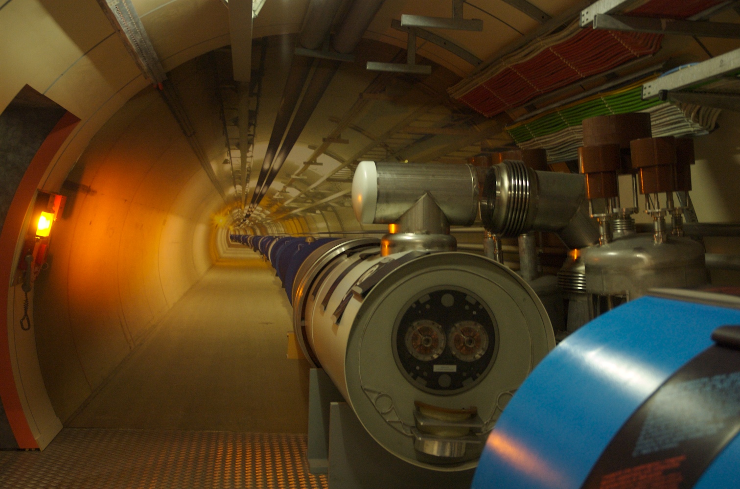 Interior of a CERN particle accelerator tunnel with scientific equipment along the curved passage.